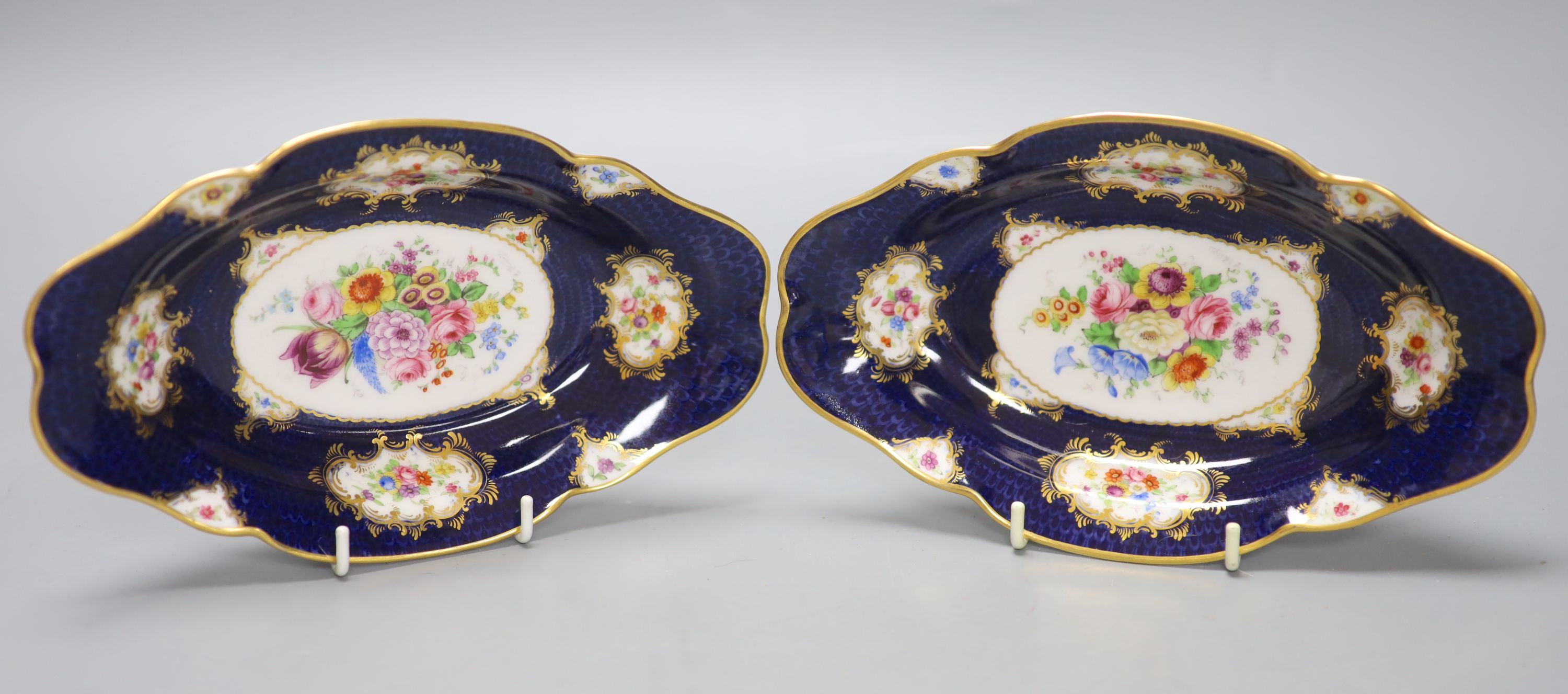 A pair of Royal Worcester blue ground floral painted dishes by E Phillips, signed date code for 1894, length 21cm